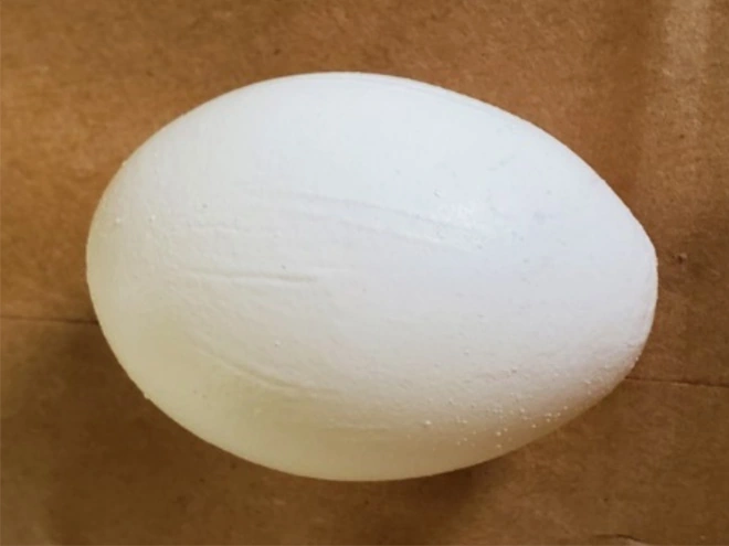 A white egg with ridges and wrinkles across the shell.