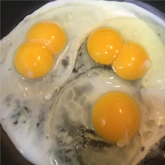 Two double-yolk chicken eggs and one single-yolk egg · shown cooking